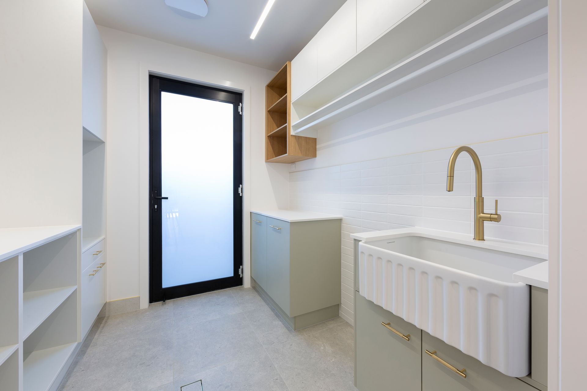 A laundry room with a sink , cabinets , and a door.
