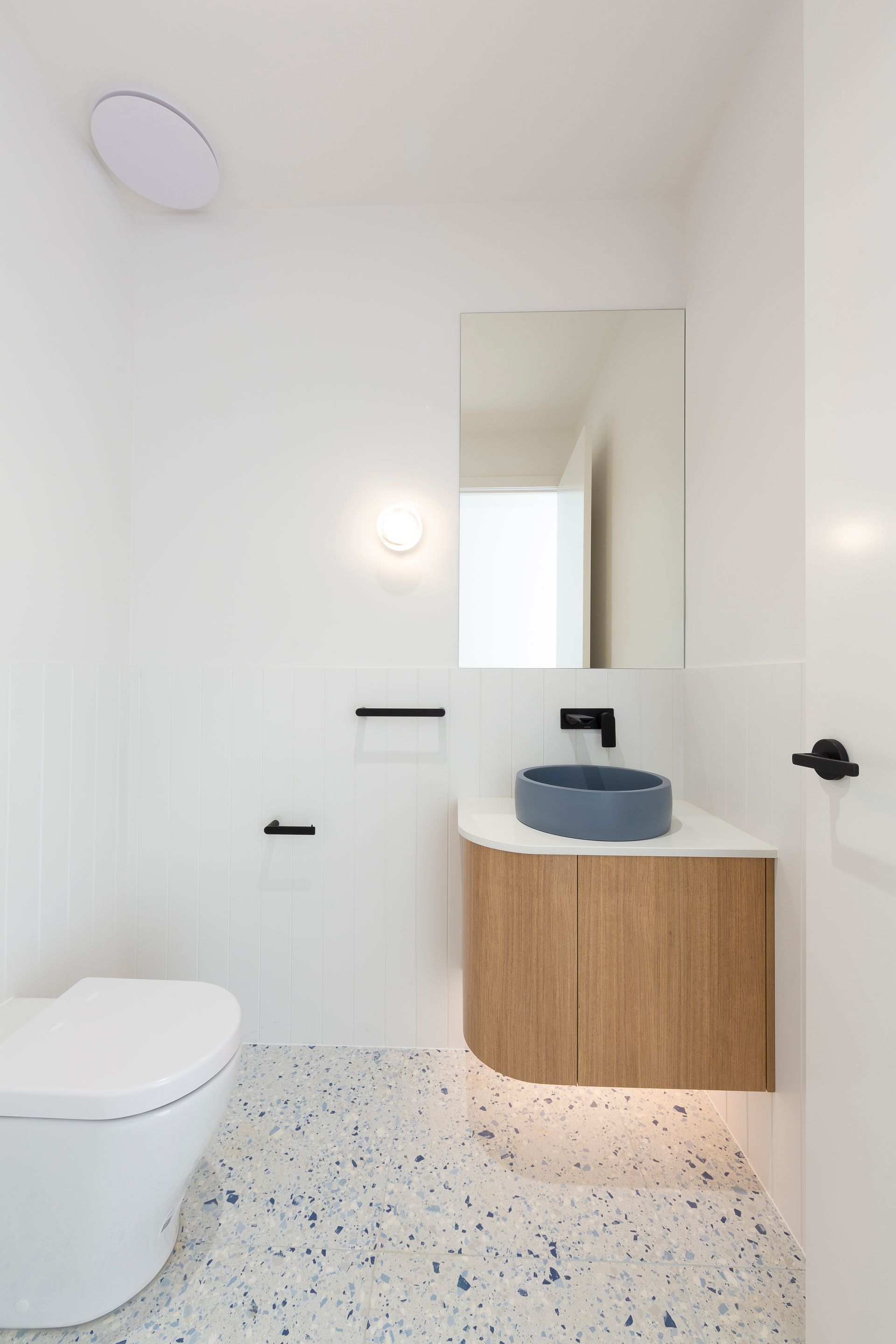 A bathroom with a toilet , sink and mirror.