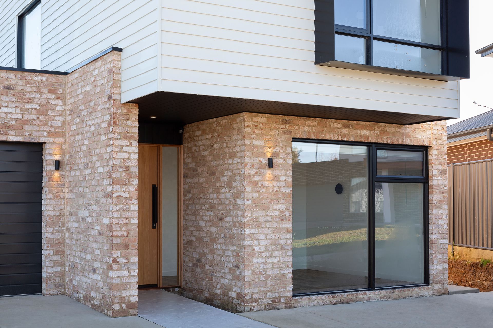 A modern house with a brick facade and a black garage door.