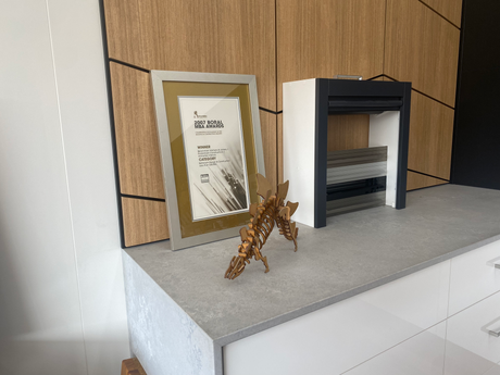 A picture frame is sitting on top of a counter with a miniature wooden dinosaur