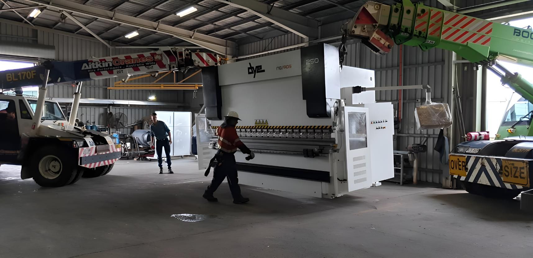 A Big Machine Being Lifted By 2 Cranes In A Warehouse — Brian Martin's Sheet Metal In North Mackay, QLD