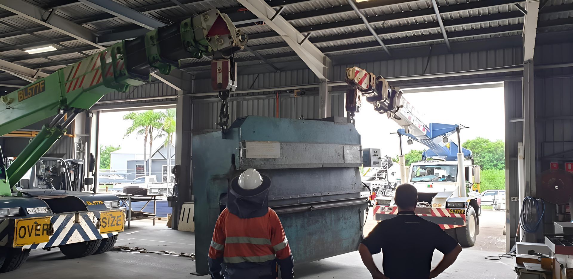 A Man Is Standing In Front Of A Machine In A Warehouse — Brian Martin's Sheet Metal In North Mackay, QLD