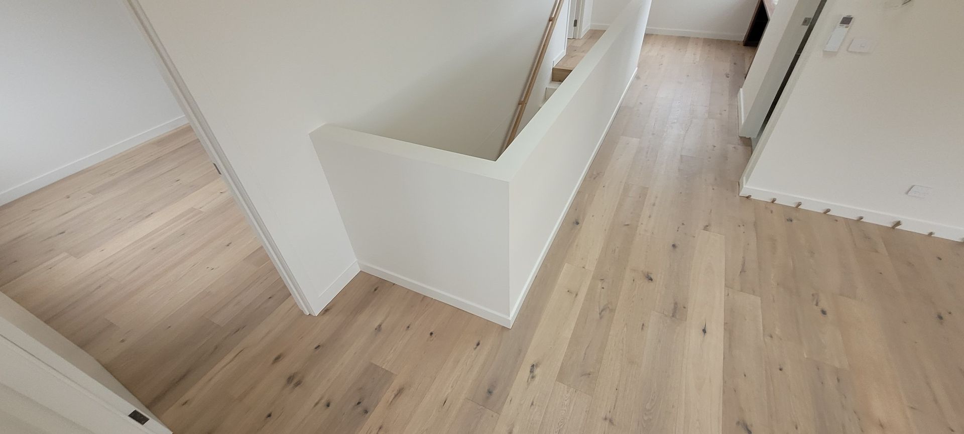 Light wood floor with white walls and a stairwell.