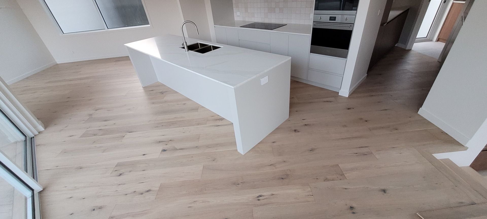 Modern kitchen with a white island and light wood flooring.