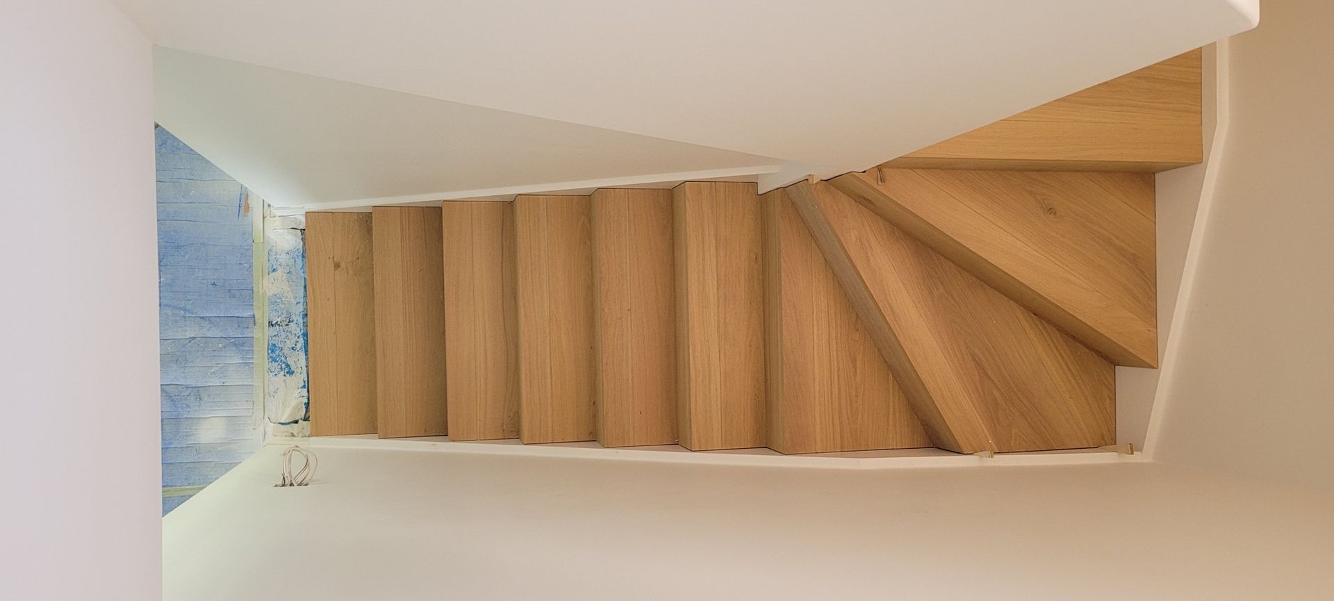 Wooden stairs with a blue wall on the side. The view is from above.