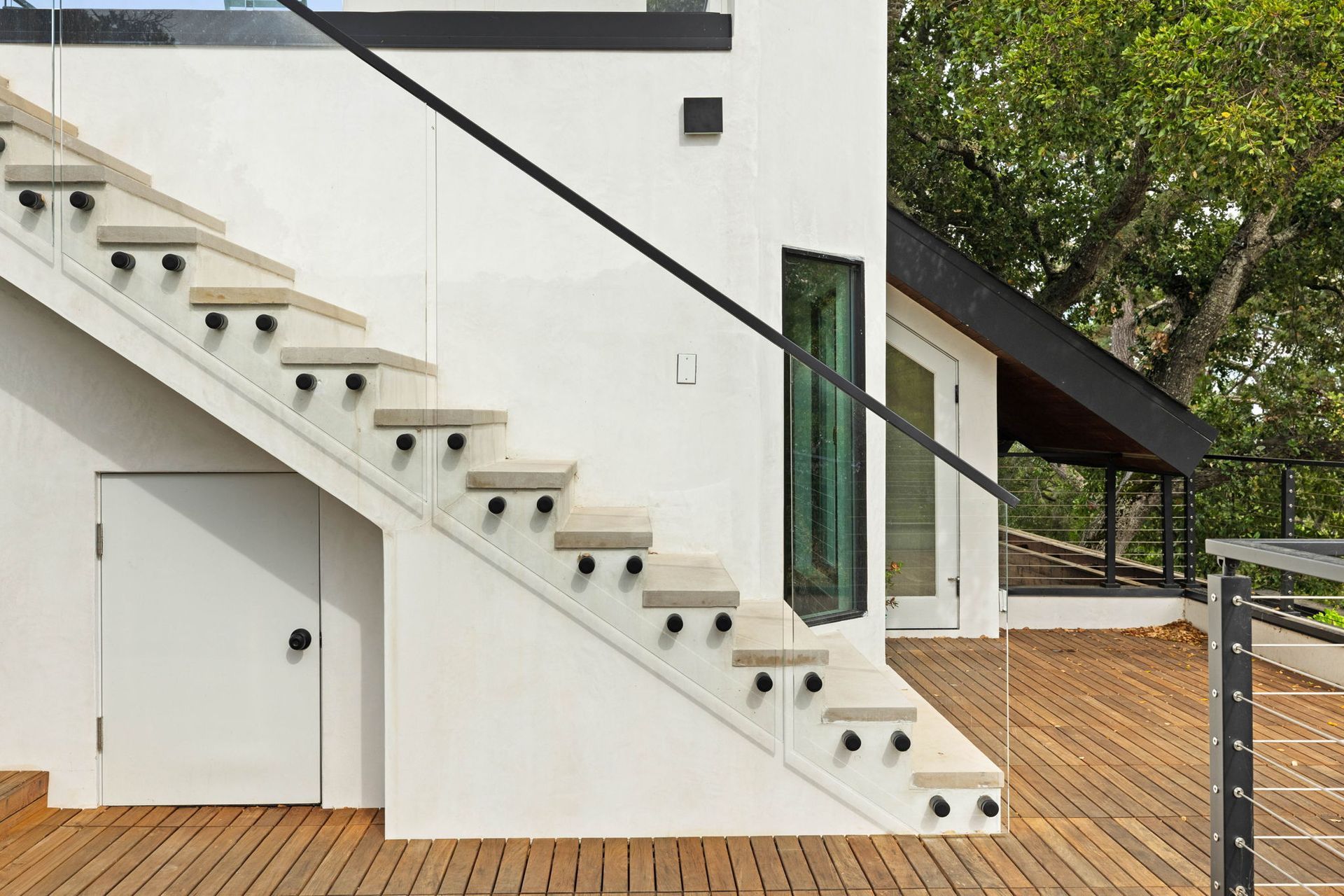 Exterior staircase with concrete steps, black handrail, and white building facade.