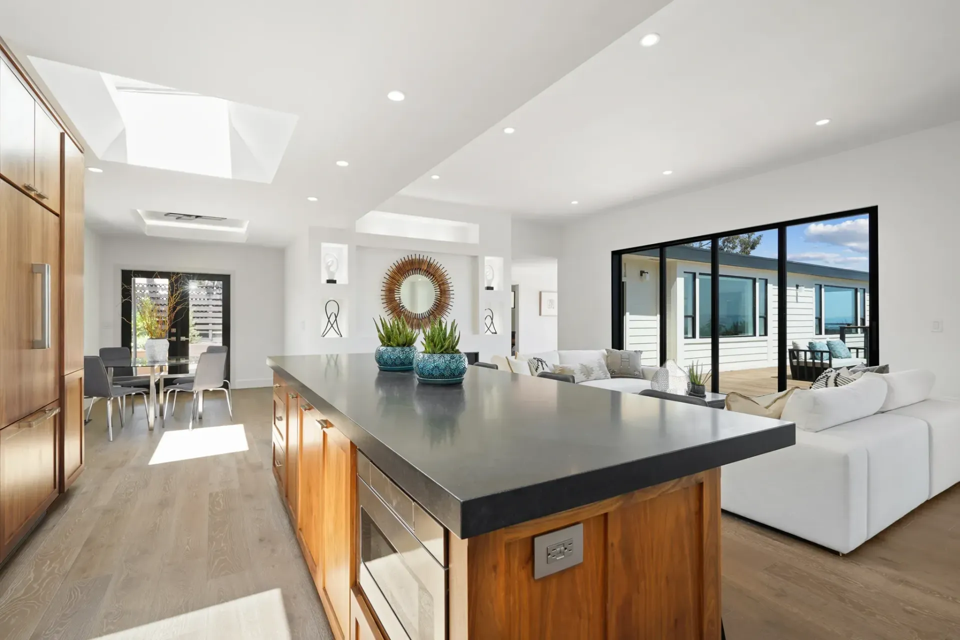 Spacious kitchen with wood cabinets, island, and seating area. Large windows and skylight provide ample light.