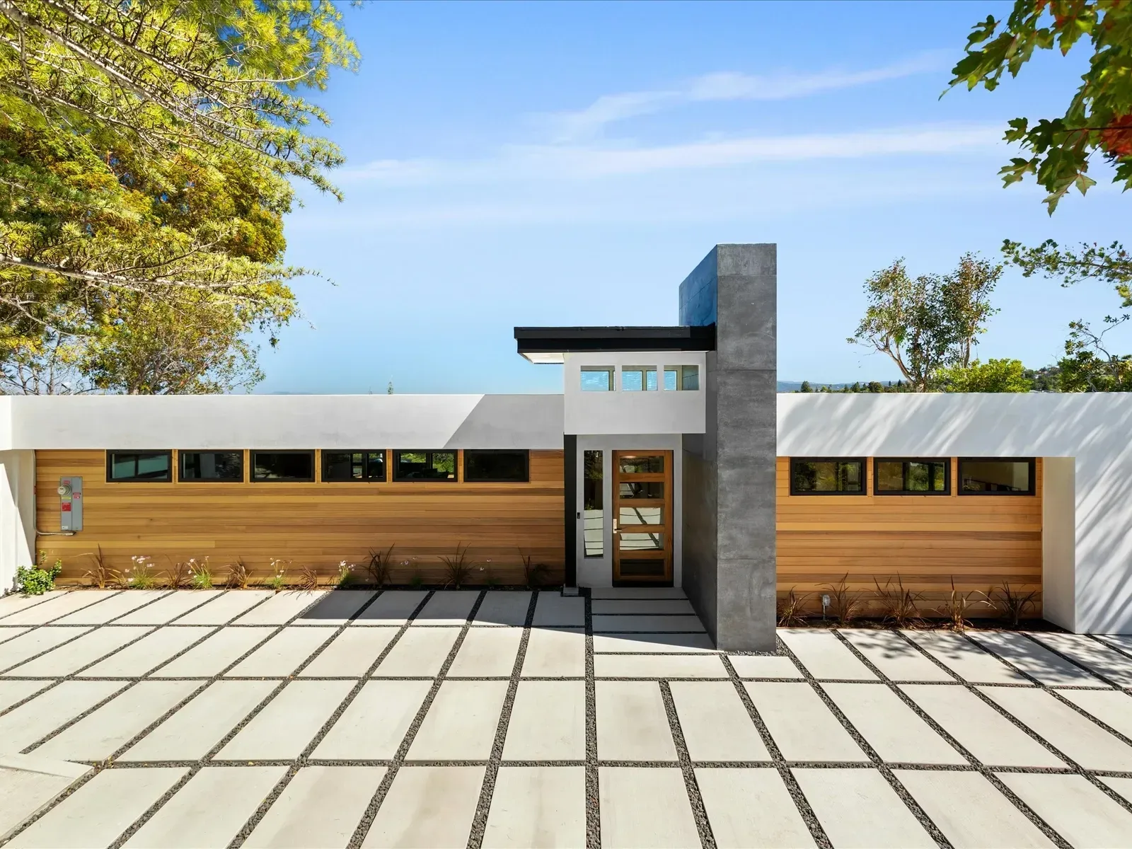 Modern home exterior with wooden panels and concrete driveway.