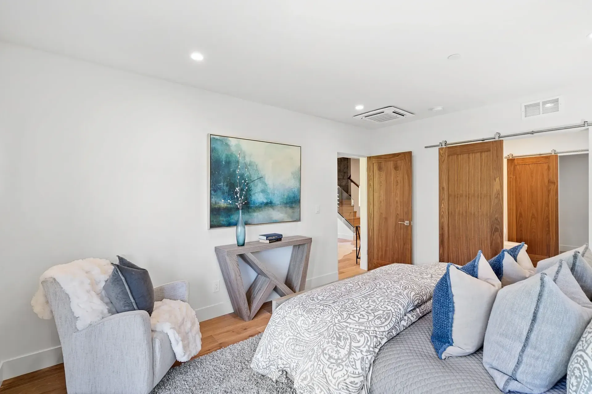 Bedroom with a bed, chair, artwork, and wooden doors.