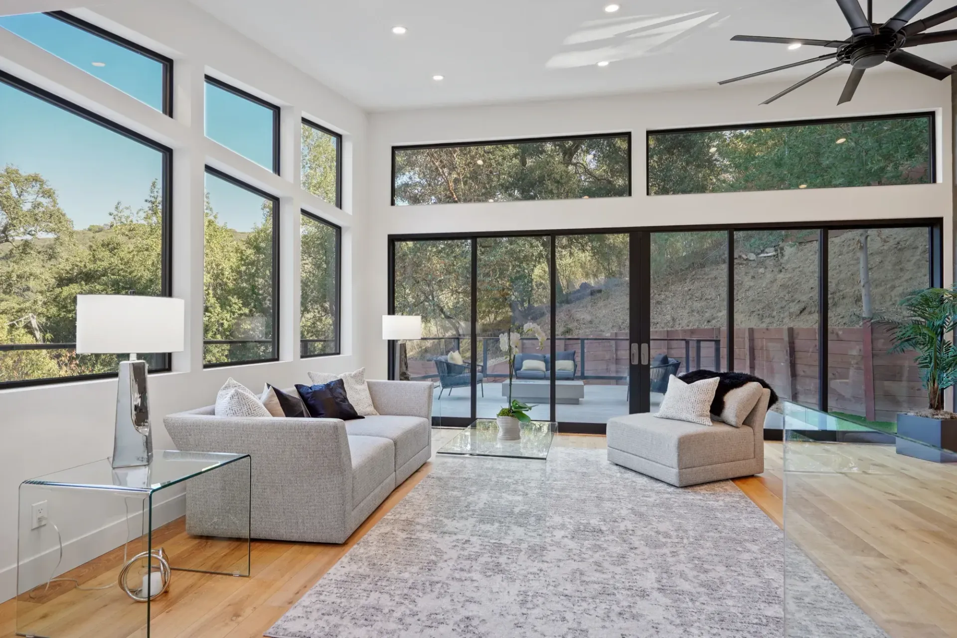 Living room with large windows, light gray sofa, and modern furniture.