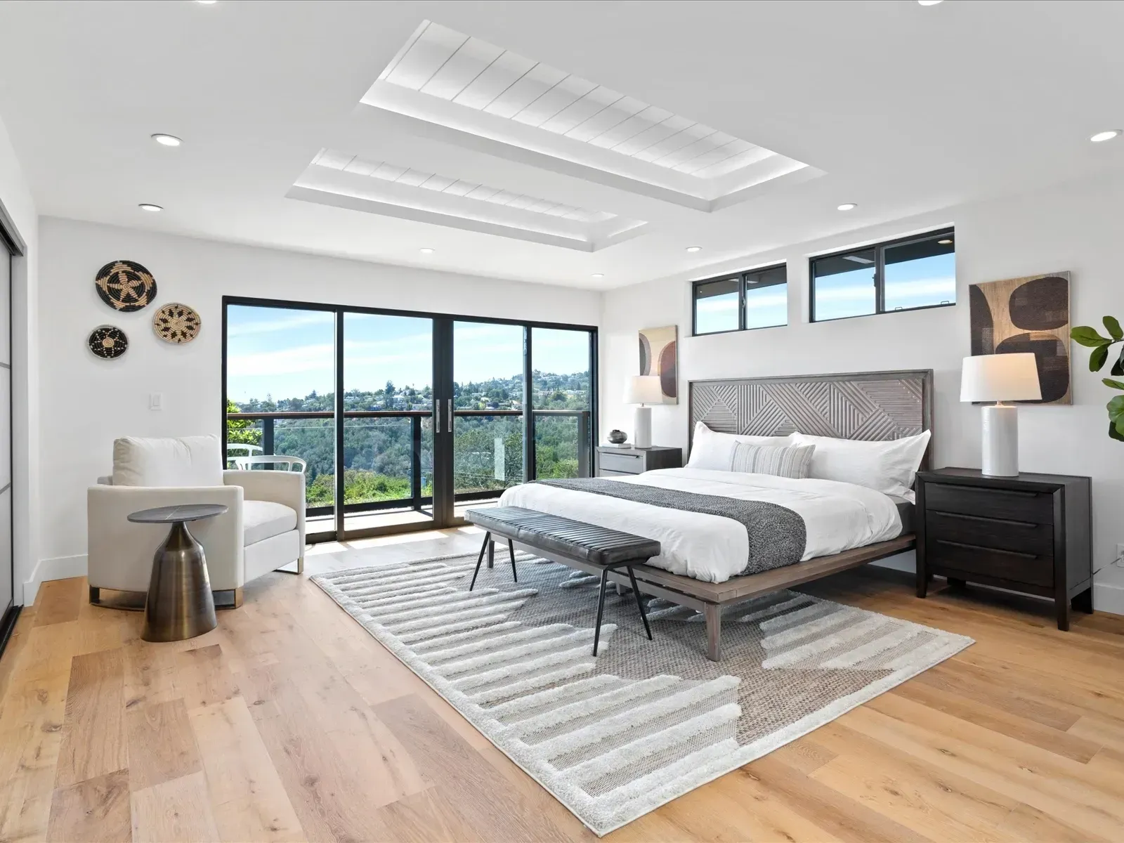 Spacious bedroom with light wood floors, large windows, and a bed facing the view.