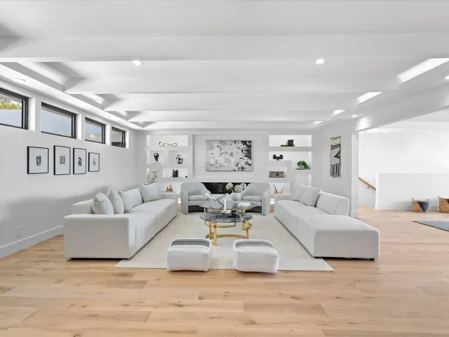 Spacious, modern living room with light-colored sofas, hardwood floors, and built-in shelving.