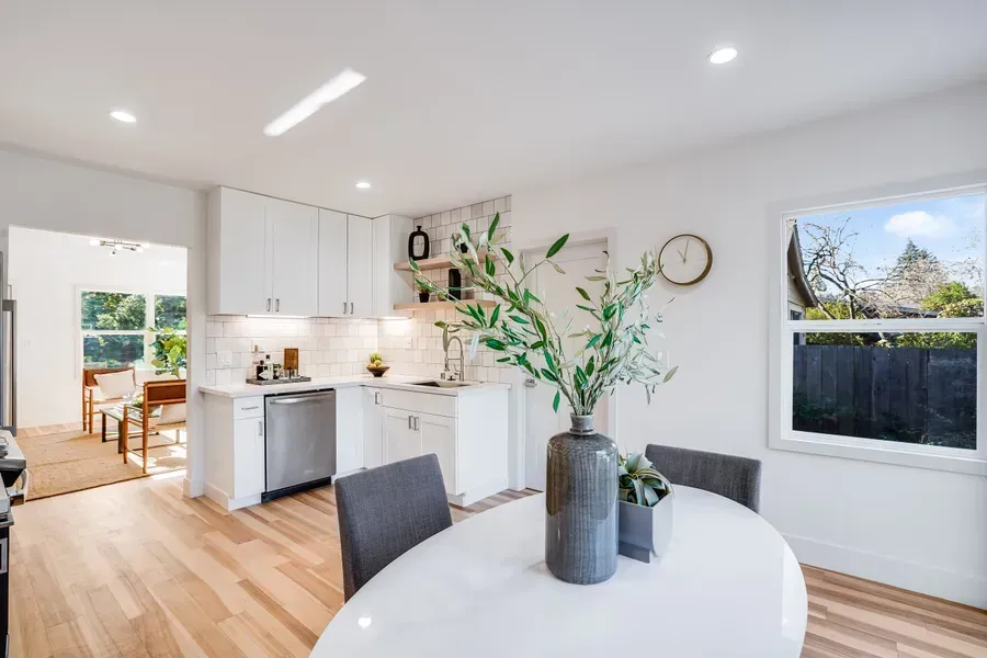 Bright, modern kitchen with white cabinets, stainless steel appliances, and a dining table.