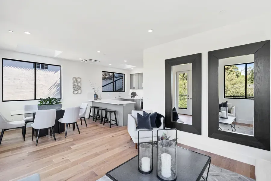 Open-concept living space with dining area, kitchen island, seating, and large mirrors reflecting outside view.