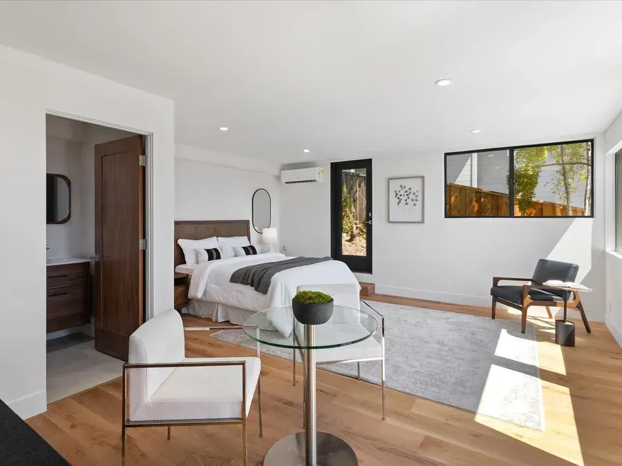 Bedroom with bed, sitting area, open doorway to bathroom, and natural light.