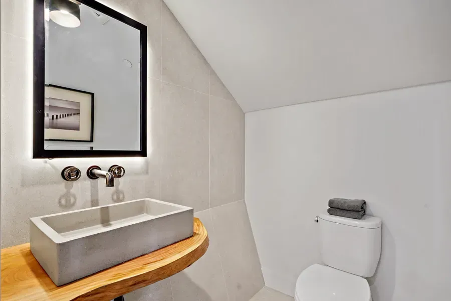 Modern bathroom with a concrete sink, wooden counter, and a toilet.