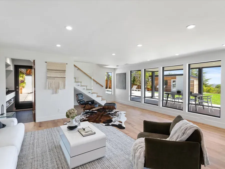 Bright living room with white walls, large windows, and hardwood floors. A cowhide rug sits on the floor.