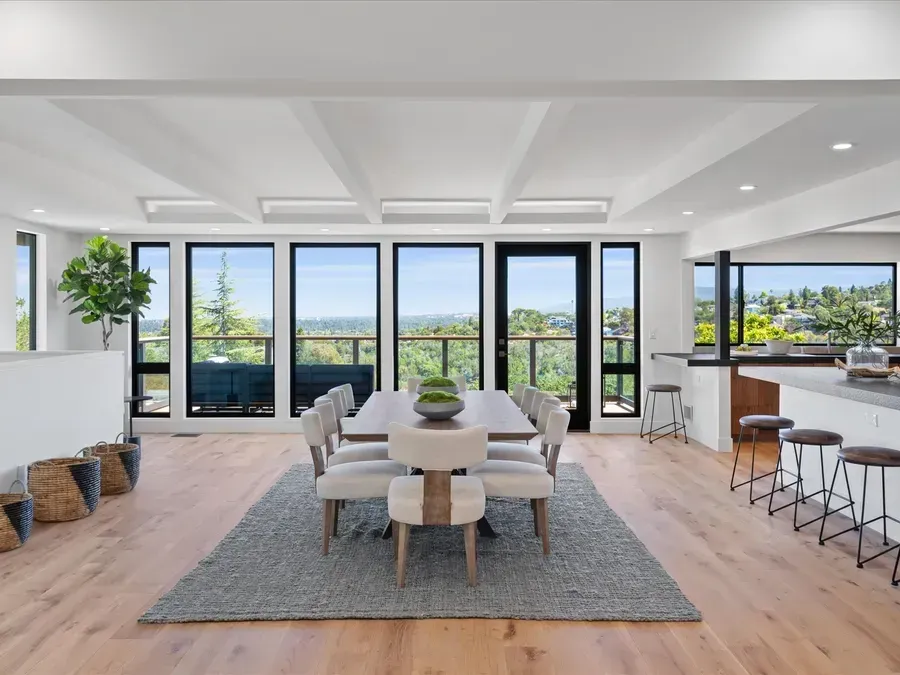 Dining room with large windows, table, chairs, rug, and scenic view.