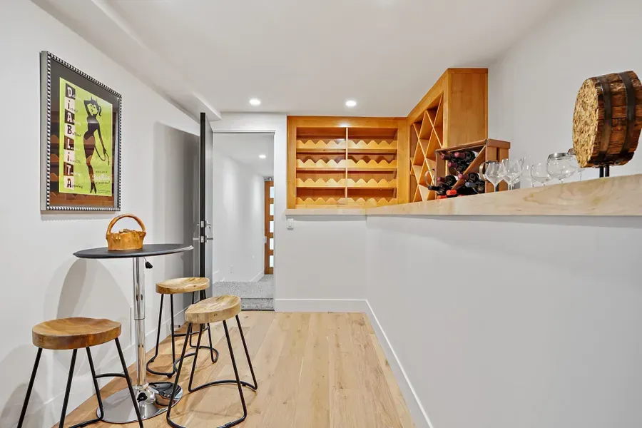Wine cellar with wooden bar, stools, and wine racks.