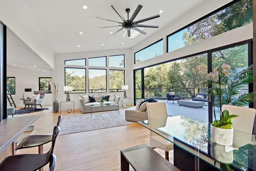 Bright modern living room with large windows, open to outdoor patio.