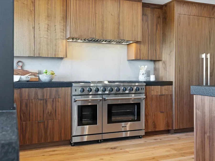 Modern kitchen with stainless steel oven, wooden cabinets, and hardwood floors.