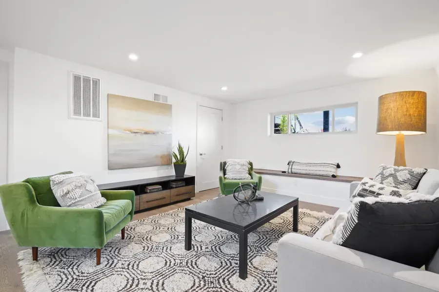 Living room with green and white furniture, abstract art, and a patterned rug.