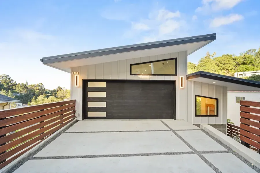 Modern home with angled roof, gray garage door, and a concrete driveway.