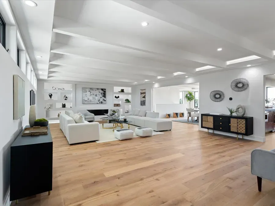 Spacious, bright living room with white walls, wood floors, and white sectional sofa.