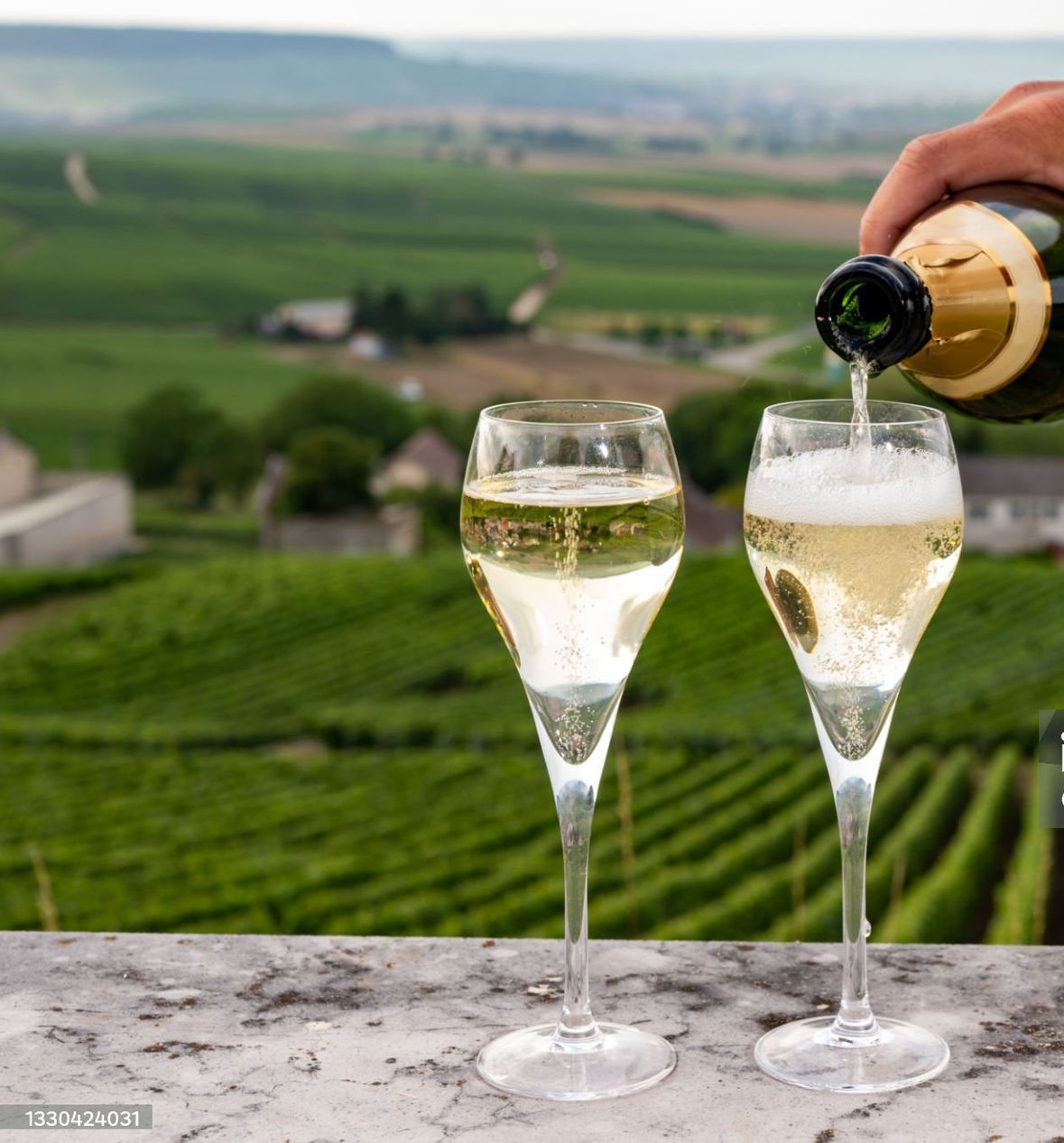 Glasses of Champagne being poured in a vineyard, representing wine tasting experiences in the Reims region.