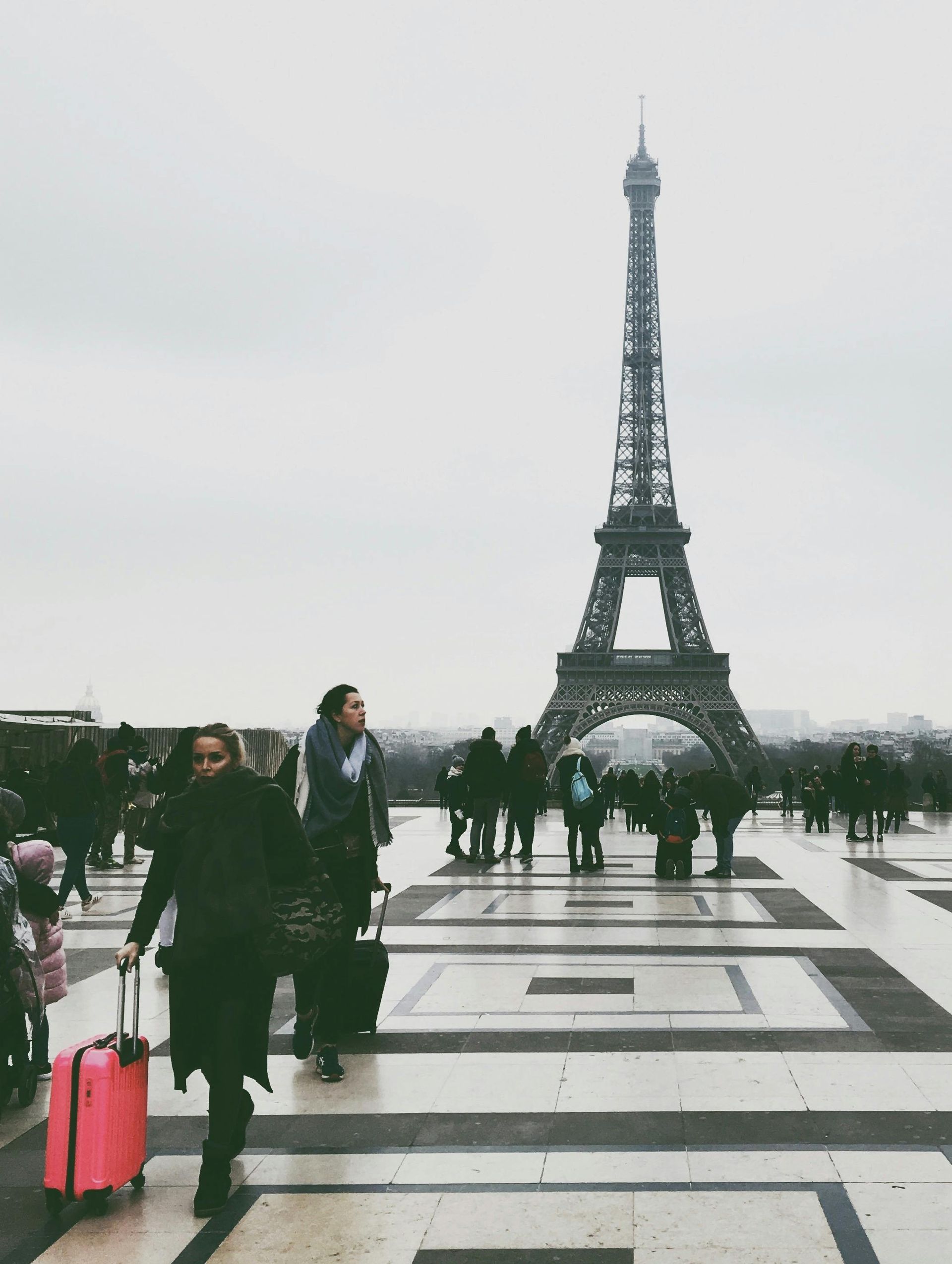 A bustling scene at Trocadéro in Paris, with visitors admiring the Eiffel Tower on a cloudy day