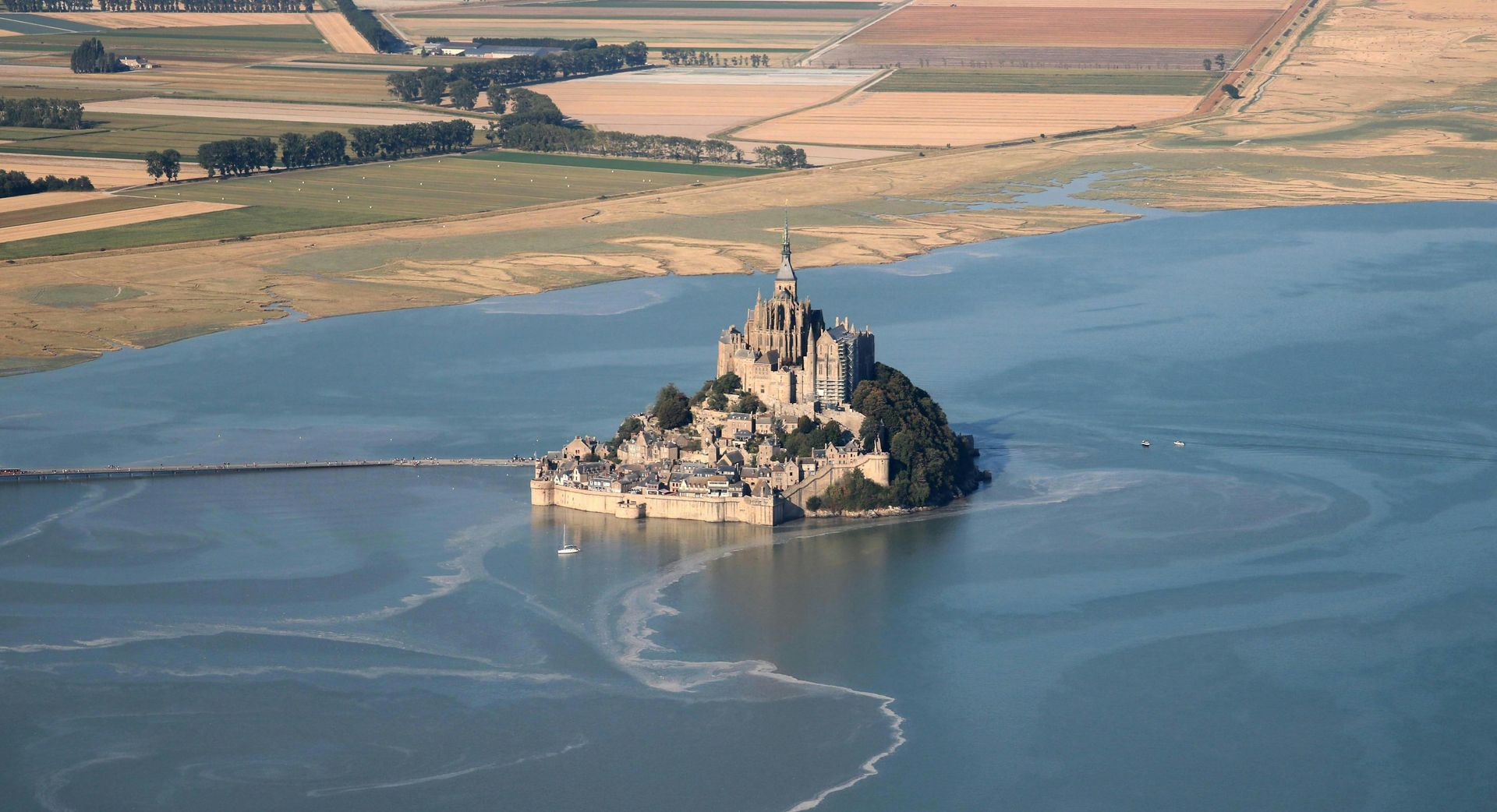 Aerial view of Mont Saint Michel, the famous medieval island and abbey in Normandy, France, surrounded by tidal waters.