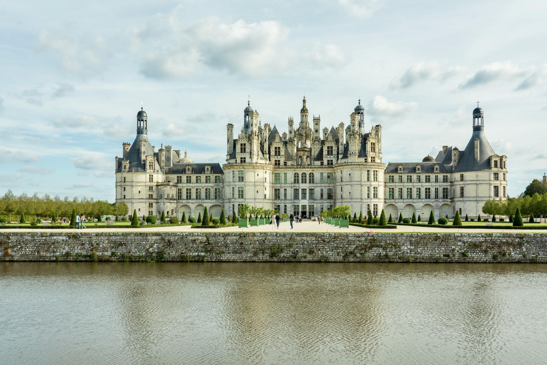 The stunning Château de Chambord in the Loire Valley, reflecting on the water under a bright sky