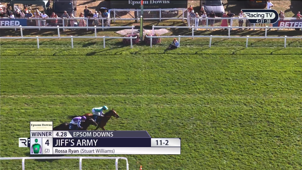 Horse race at Epsom Downs: Horses racing, rider in green leading, crowds in background.