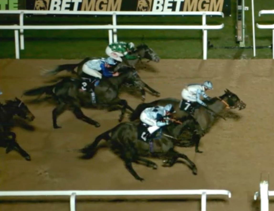 Horses racing on a dirt track, jockeys in colorful silks.
