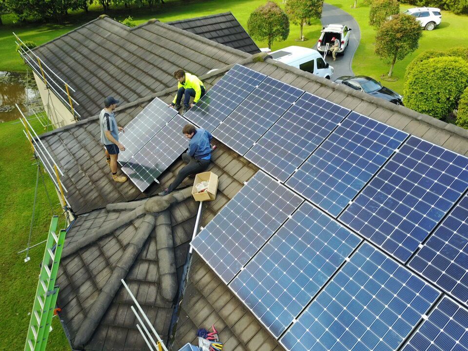 solar panels being installed by three men on a roof — Solar Services in Erina, NSW