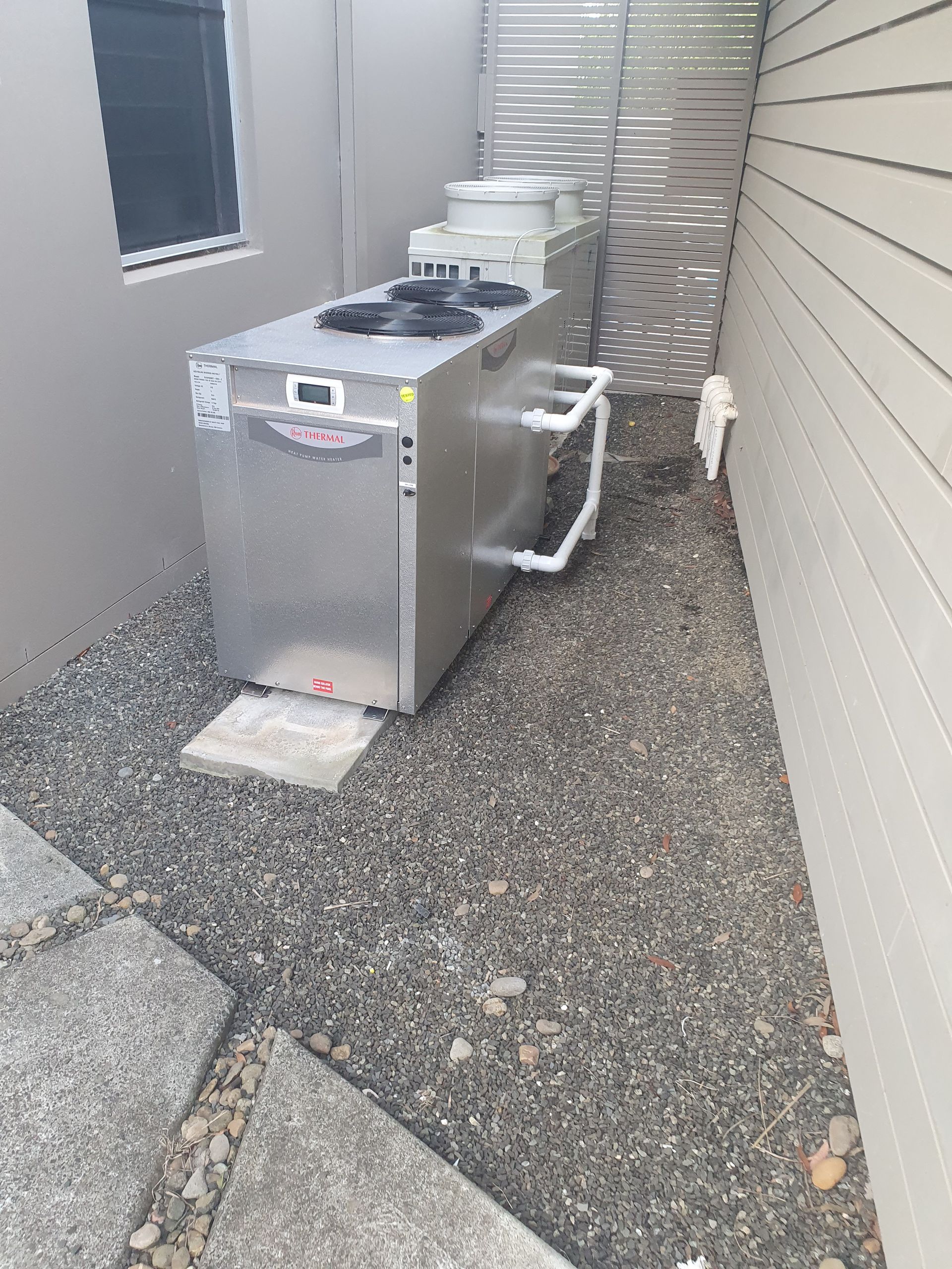 A pool heating pump next to a fence — Solar Services in Bateau Bay, NSW