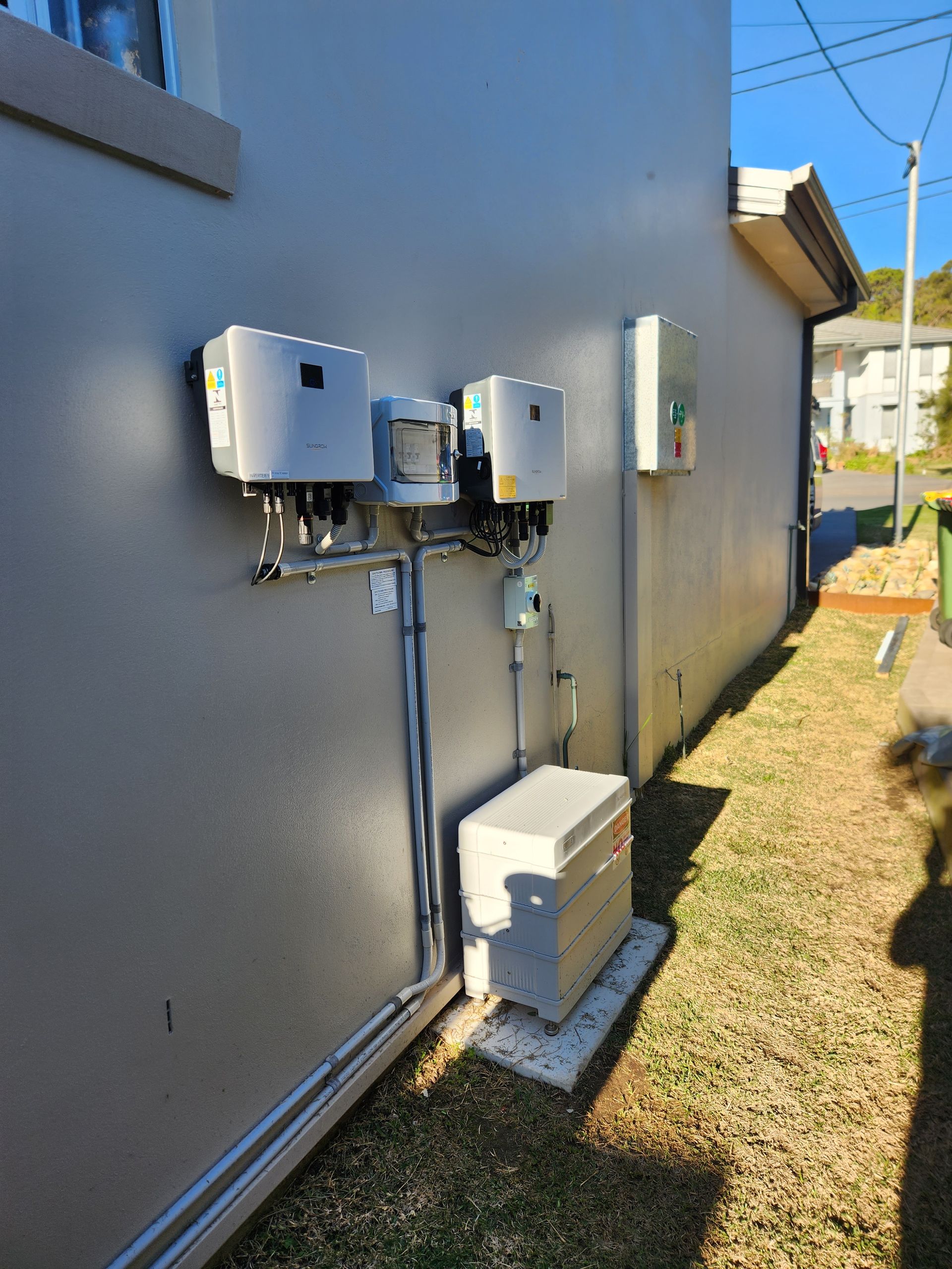 Exterior wall with solar batteries mounted beside a house — Solar Services in Erina, NSW