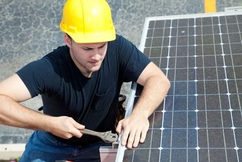 Worker In A Yellow Hard Hat Repairing A Solar Panel — Solar Services in Erina, NSW