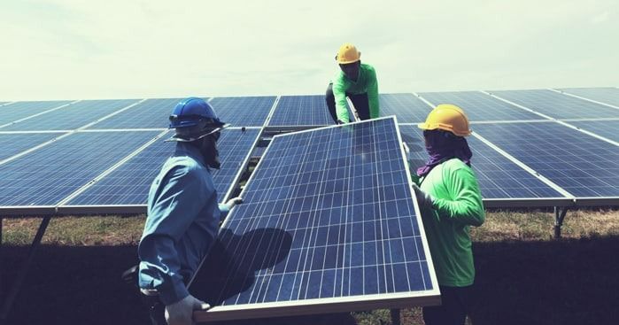 Workers Installing Solar Panels In A Field Under A Sky — Solar Services in Erina, NSW