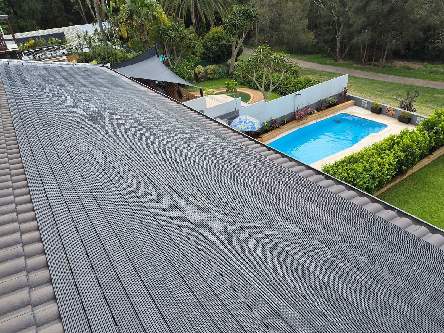 Roof With Patterned Gray Shingles Overlooking A Backyard Pool — Solar Services in Erina, NSW