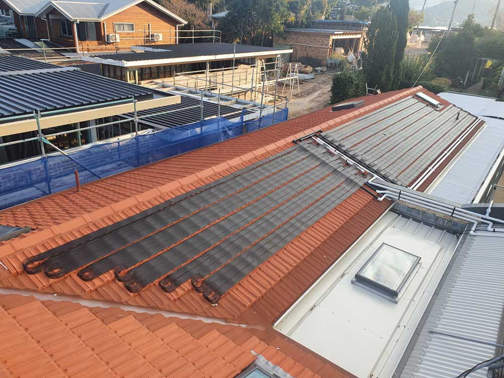 Solar thermal panels installed on a red tiled roof — Solar Services in Erina, NSW