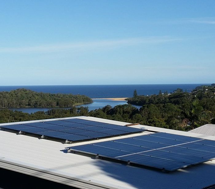 Solar Panels Are on the Roof of a Building With a View of the Ocean — Solar Services in Erina, NSW