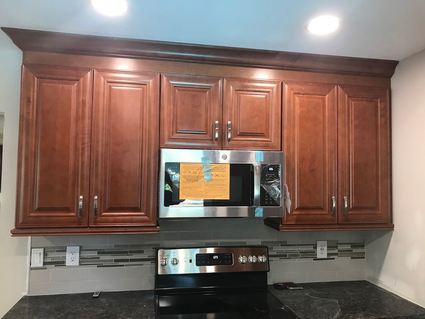 Brown kitchen cabinets with a microwave and stove.