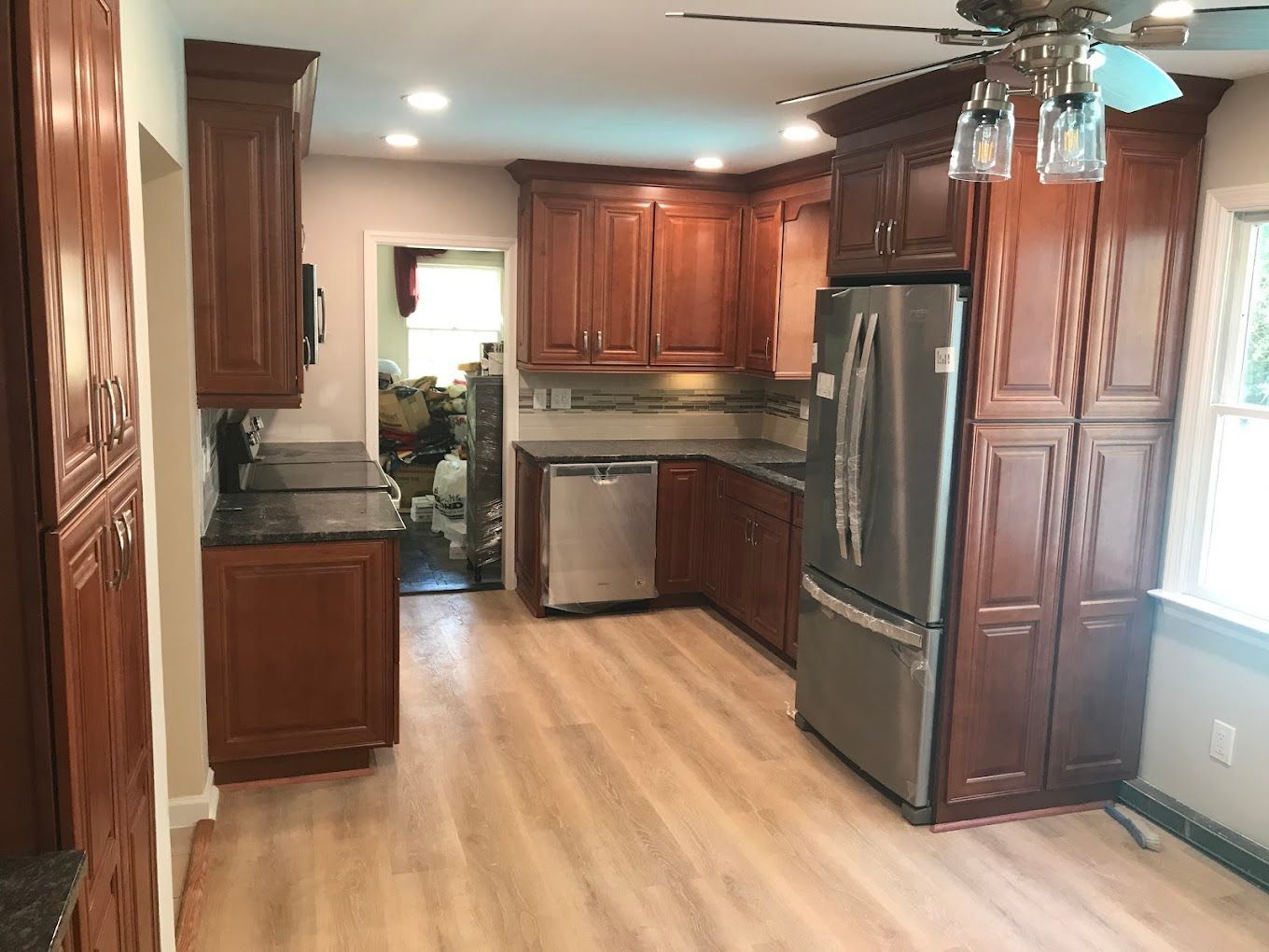 A remodeled kitchen with dark wood cabinets, stainless steel appliances, and light wood-look flooring.