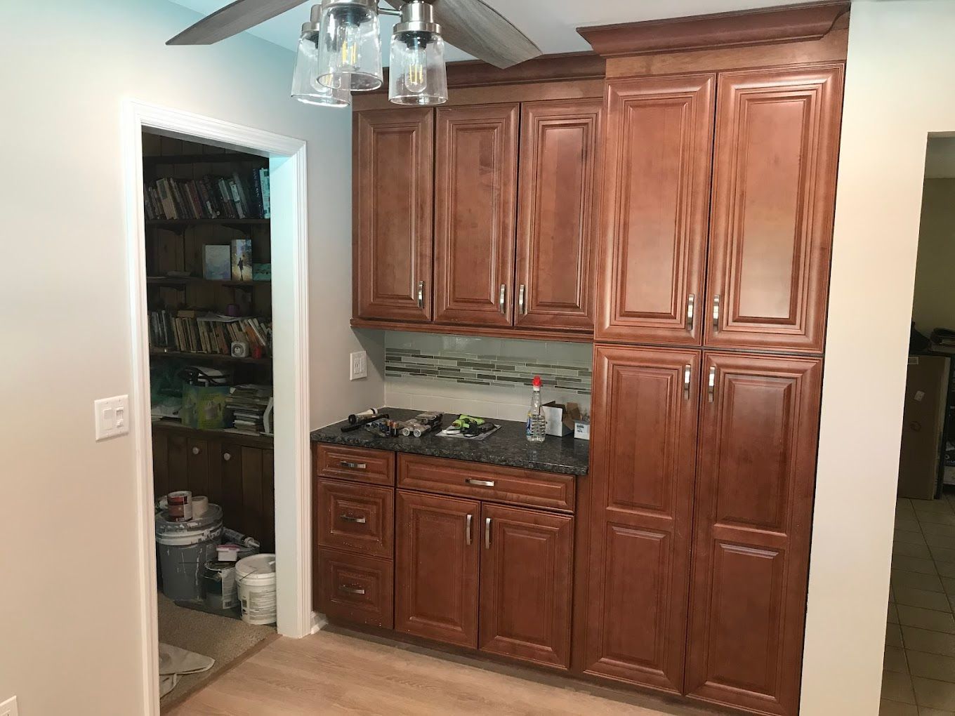 Brown kitchen cabinets and countertops, built-in storage with a doorway to a pantry.
