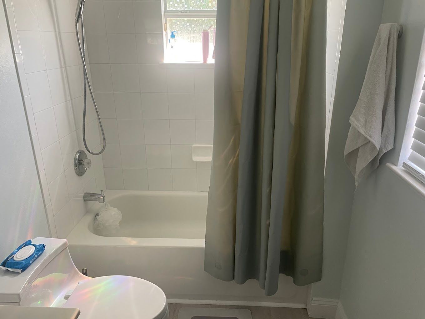 Small bathroom with a tub and shower, light blue walls, and a closed shower curtain.