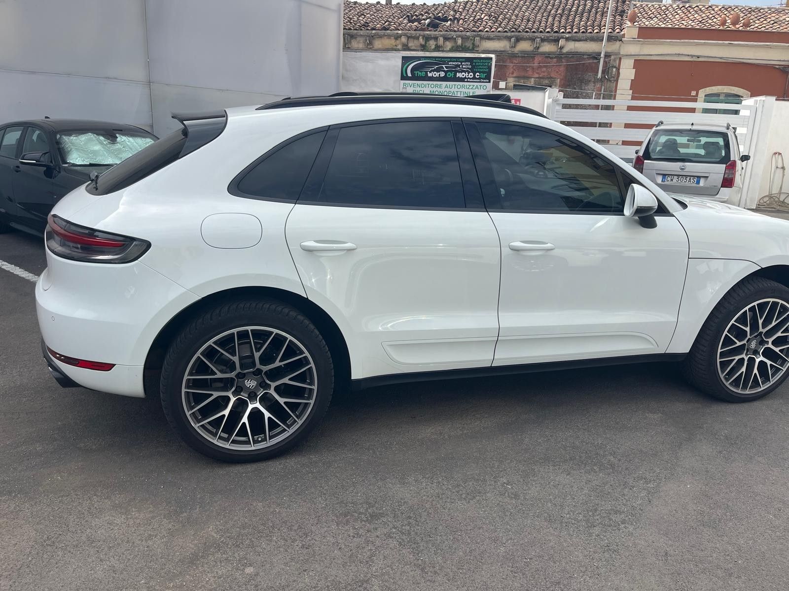 SUV Porsche Macan bianco con cerchi neri parcheggiato all'esterno.