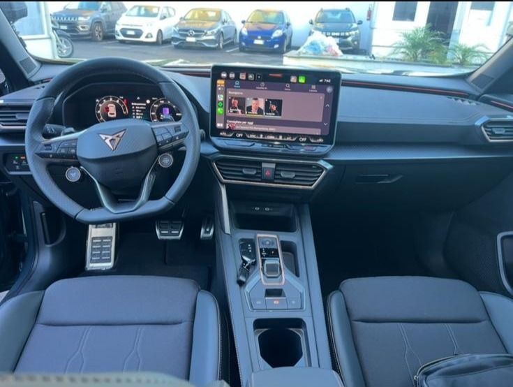 Interno di un'auto CUPRA nera, in cui sono visibili il cruscotto, il volante, il grande schermo dell'infotainment e i sedili.