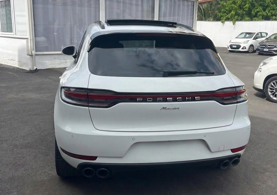 SUV Porsche Macan bianco con finiture nere, parcheggiato all'aperto.