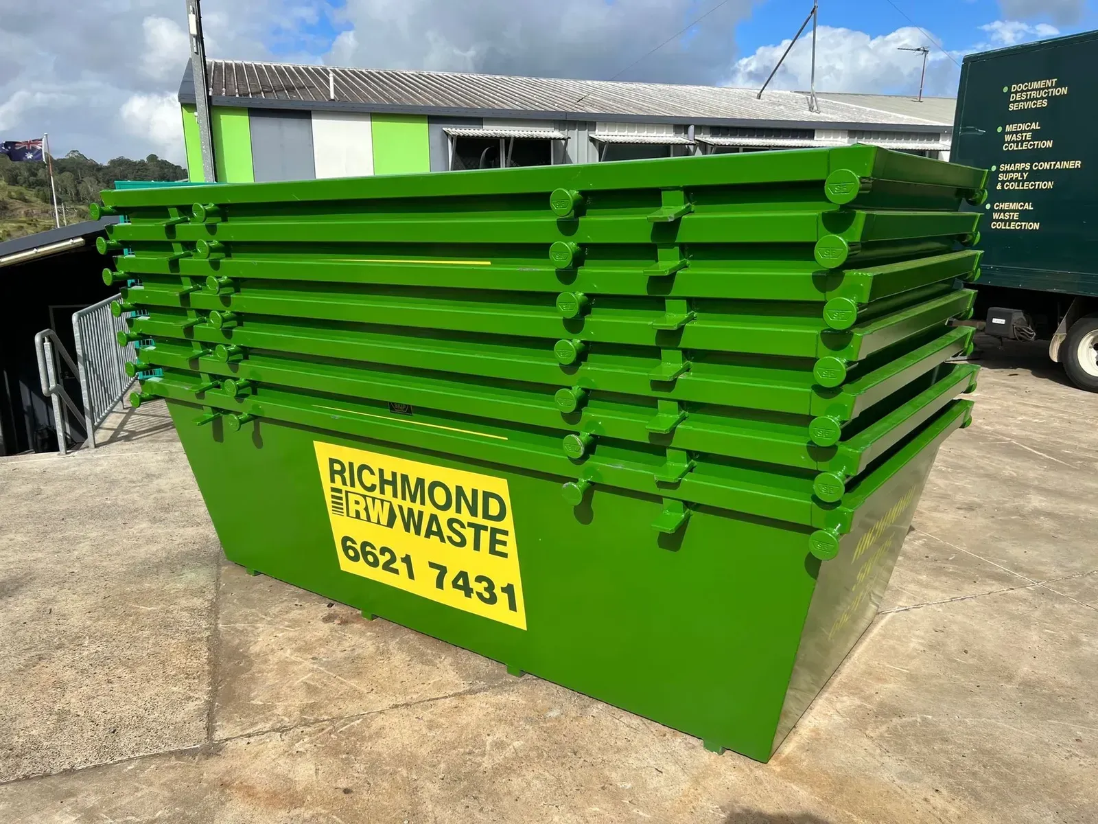 Green Waste Bins Stacked, With Richmond Skip Waste Contact Info. Outdoors, Daytime — Hasti Skips in Bangalow, NSW